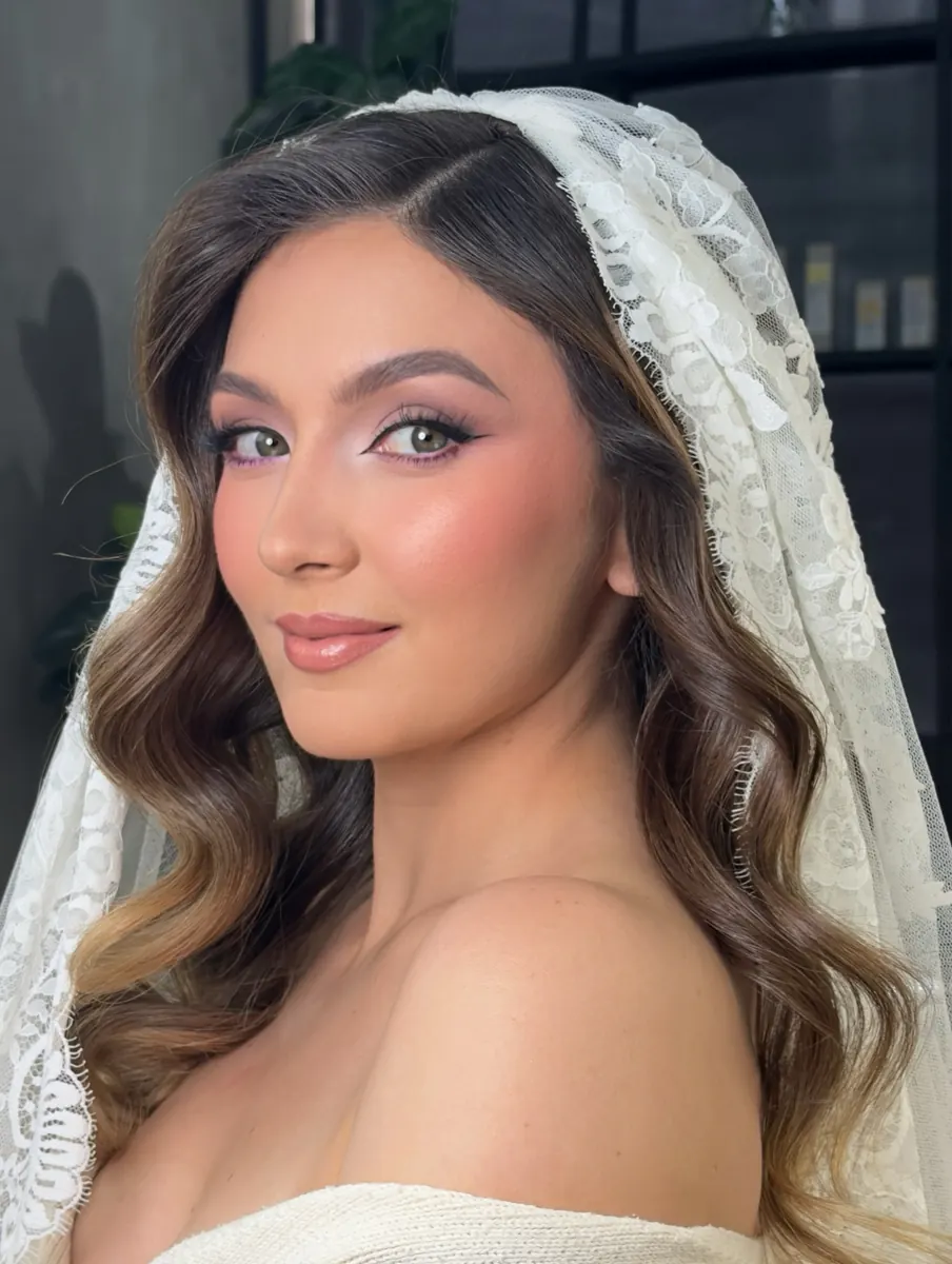 Novia con velo de encaje, maquillaje luminoso y ondas
